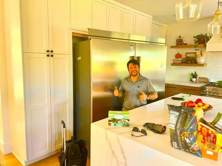 technician next to a stainless steel refrigerator in a kitchen